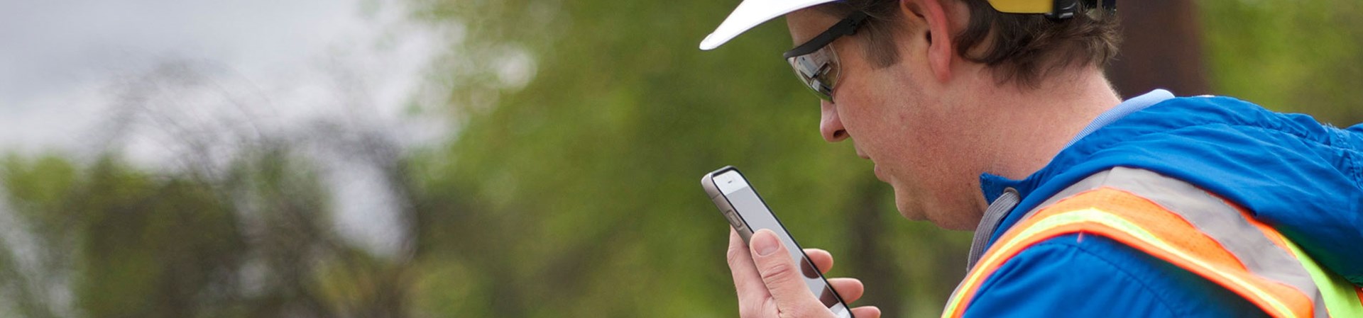 Man Wearing A Hard Hat Speaks Into A Mobile Phone