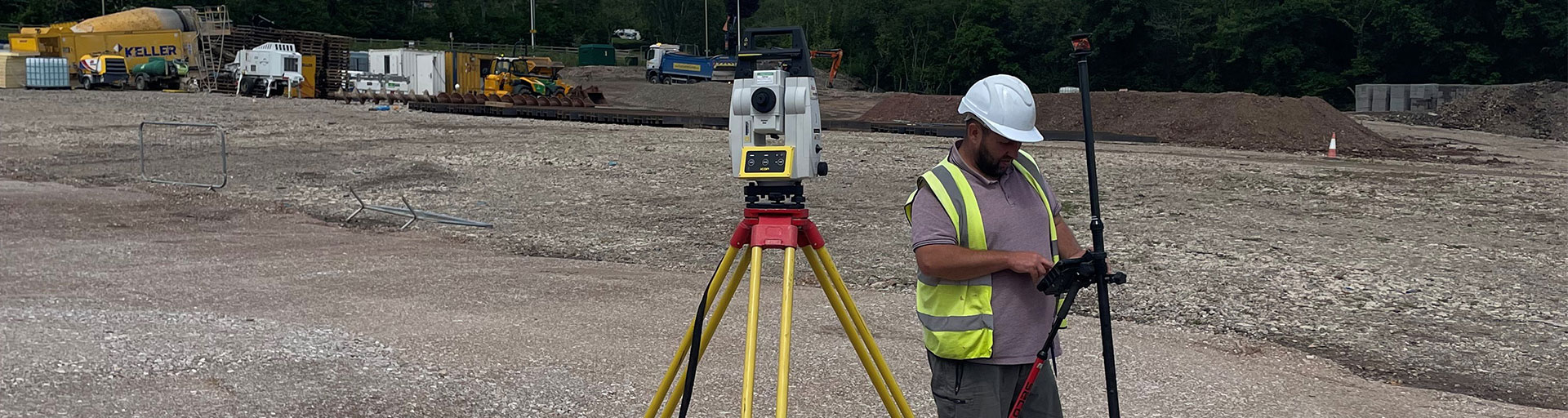 Robotic Total Station Onsite At Coed Drew Housing Development Being Used By A Surveyor Standing Next To It