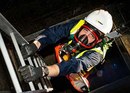 Man With Breathing Apparatus Climbing Into Confined Space