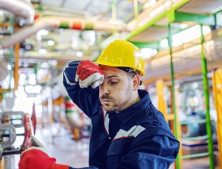 Worker In Factory Wiping Sweat From Brow