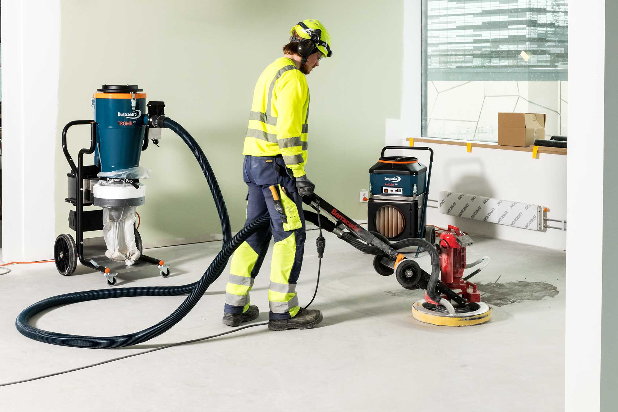 Worker Sanding A Building Floor Next To An Air Filtration Unit