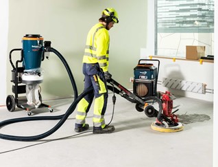 Worker Sanding A Building Floor Next To An Air Filtration Unit