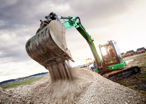 Sunbelt Rentals green excavator with bucket dropping gravel