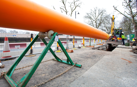 Orange pipe being assessed by construction workers