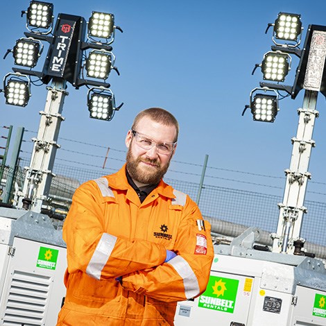 Sunbelt Rentals Engineer Stood In Front Of Tower Lights At An Industrial Site