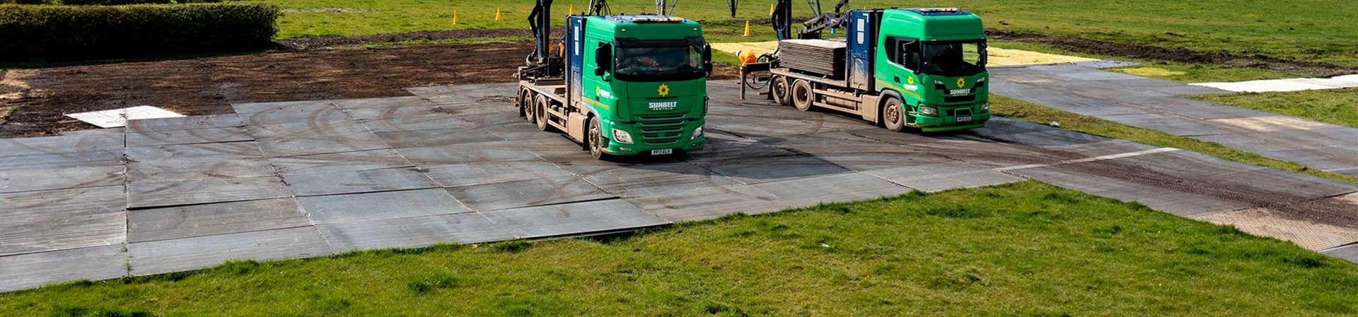Two Trakway Trucks Laying Down Temporary Trakway On A Field