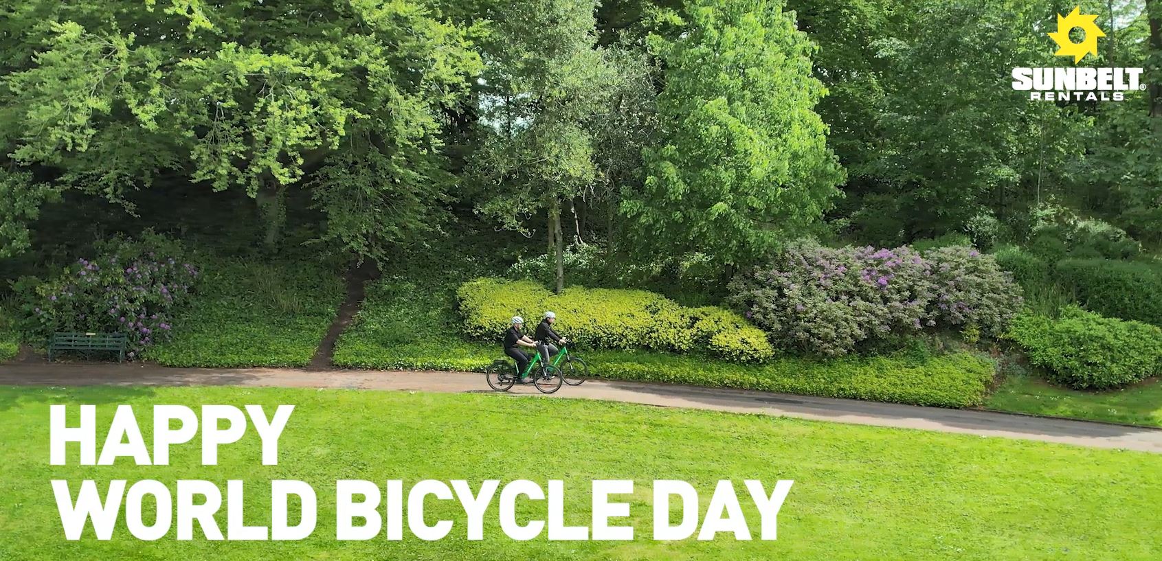 Ariel shot of a biker riding a bike in a park with text happy world bicycle day 