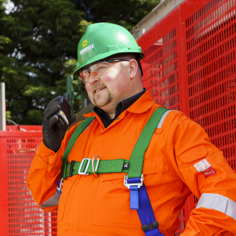 Man wearing Sunbelt Rentals helmet and safety clothing talking into radio