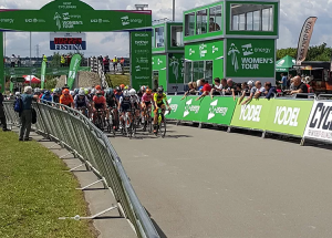 Road cycling contest with green crowd control barriers and fencing