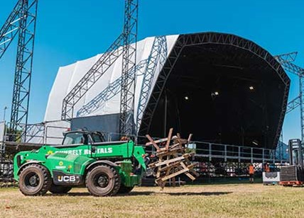 Telehandler Carrying Benches Past Event Stage