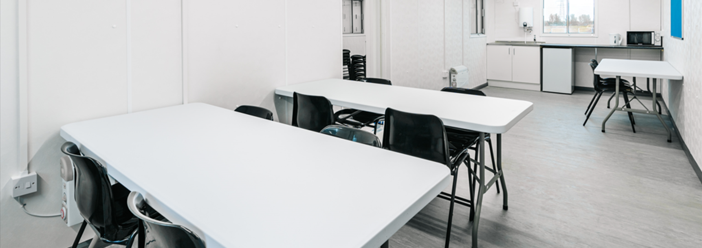 inside of a site canteen with white tables and black chairs