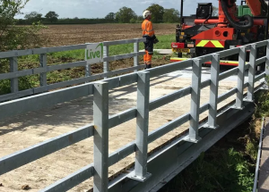 Temporary bridge over stream with worker and machine stood behind